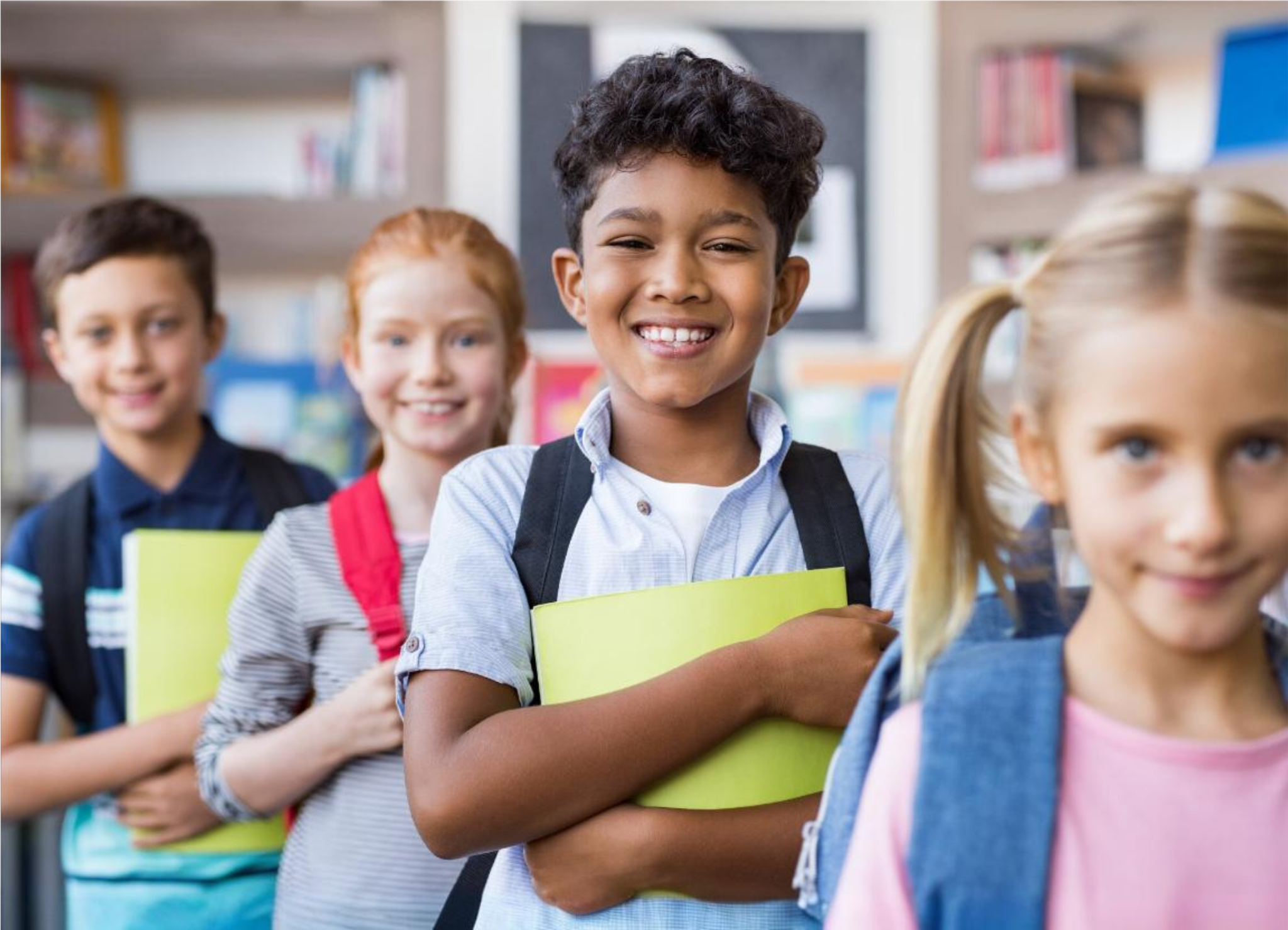 Crianças sorridentes em fila indiana em escola, segurando cadernos e mochilas